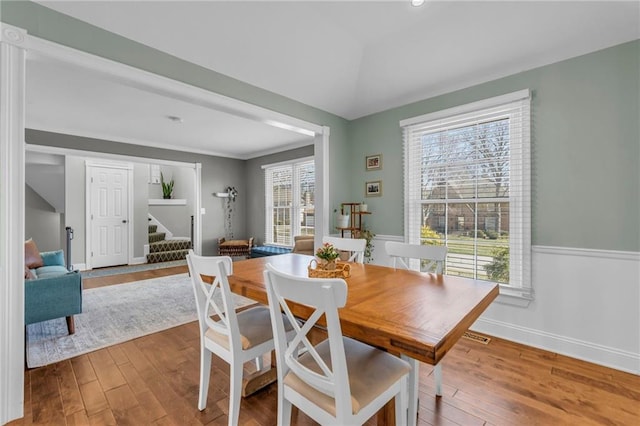 dining room with baseboards, stairway, a wainscoted wall, lofted ceiling, and wood-type flooring