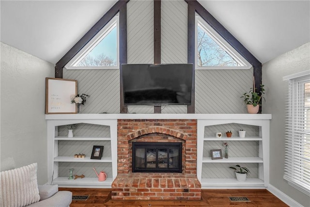 unfurnished living room featuring plenty of natural light, built in shelves, wood finished floors, and a brick fireplace