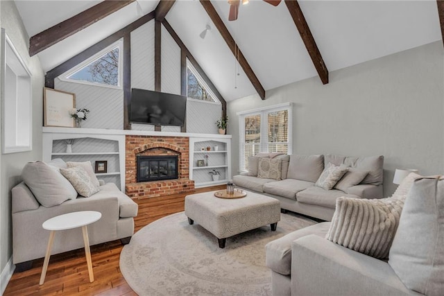 living room with beam ceiling, high vaulted ceiling, wood finished floors, a fireplace, and ceiling fan