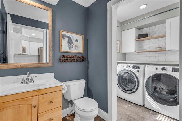 bathroom with washing machine and clothes dryer, toilet, decorative backsplash, wood finished floors, and vanity