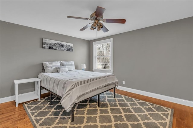 bedroom featuring wood finished floors, baseboards, and ceiling fan