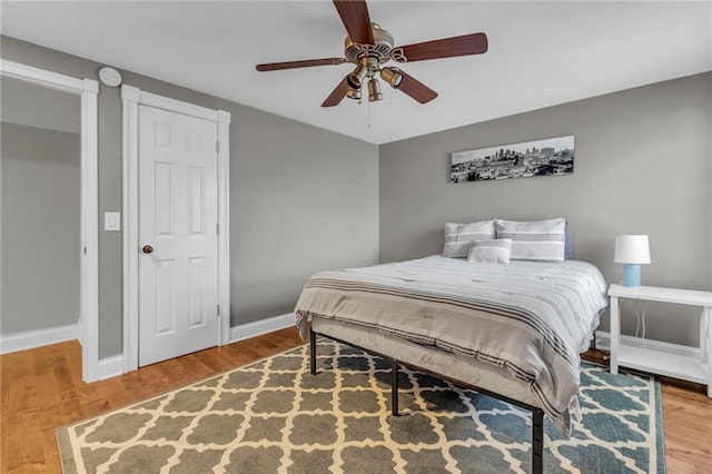 bedroom featuring ceiling fan, baseboards, and wood finished floors