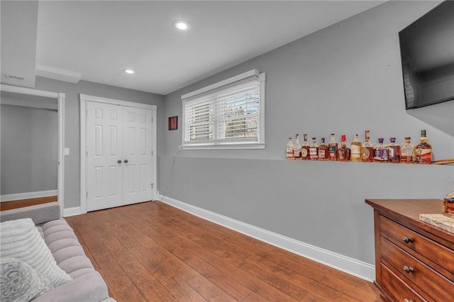 interior space featuring recessed lighting, a dry bar, baseboards, and hardwood / wood-style floors