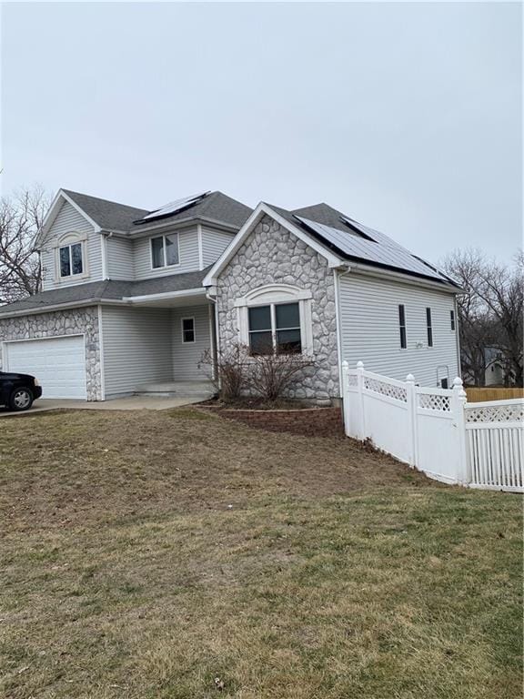 view of front facade featuring a garage, a front lawn, and solar panels