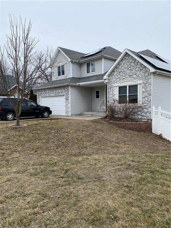 view of front of home featuring a garage, a front yard, and solar panels