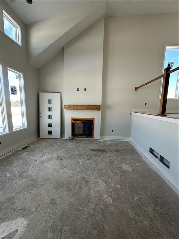 unfurnished living room with visible vents, a fireplace, high vaulted ceiling, and baseboards