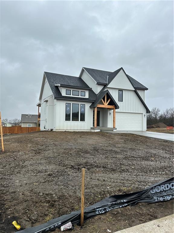 modern farmhouse style home with a garage, a shingled roof, fence, driveway, and board and batten siding