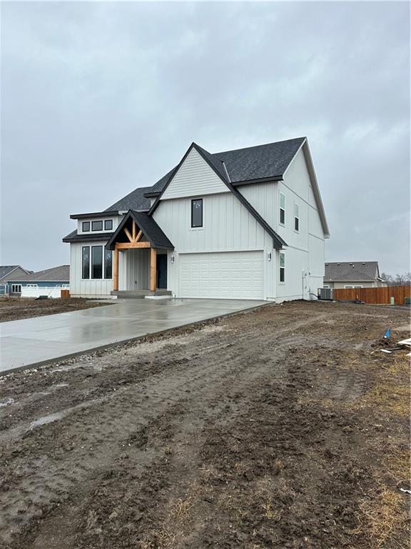 modern inspired farmhouse with driveway, central AC unit, roof with shingles, fence, and board and batten siding