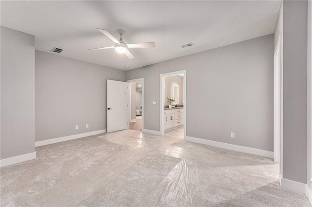 unfurnished bedroom with connected bathroom, light colored carpet, and ceiling fan