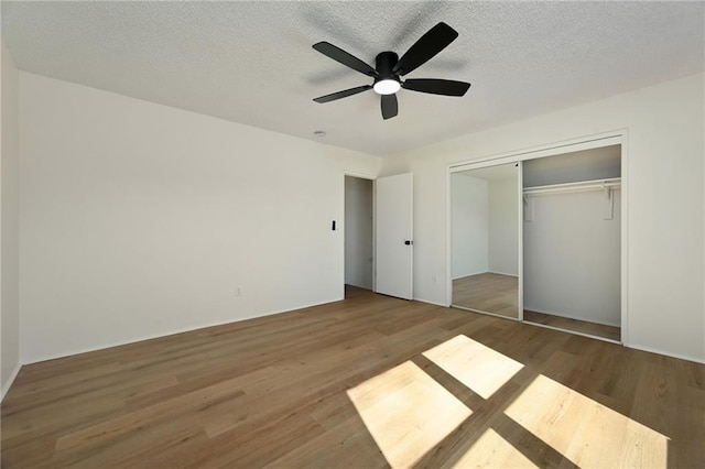 unfurnished bedroom with a closet, a textured ceiling, ceiling fan, and wood finished floors