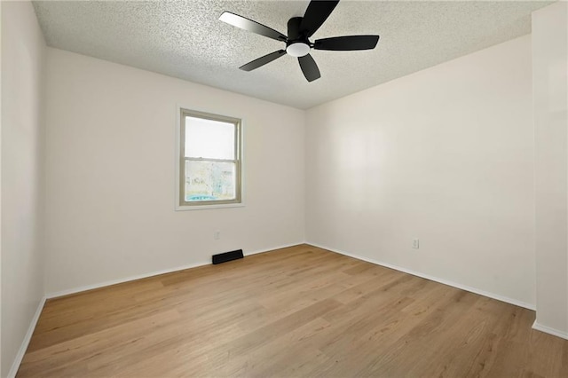 empty room with a textured ceiling, ceiling fan, and light wood-style floors