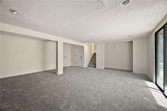 below grade area with carpet, a textured ceiling, and stairs