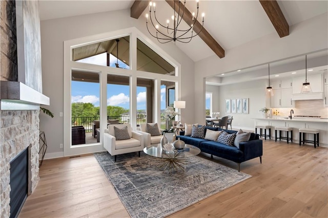 living room featuring beamed ceiling, high vaulted ceiling, light wood-type flooring, and a notable chandelier