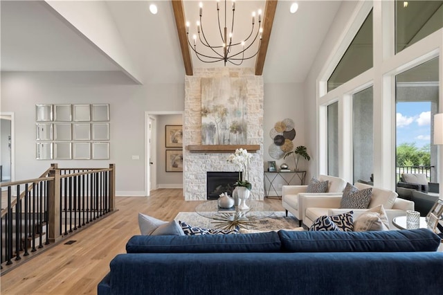 living room featuring hardwood / wood-style flooring, a stone fireplace, an inviting chandelier, and beam ceiling