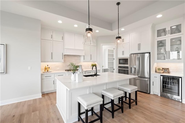 kitchen featuring wine cooler, a kitchen island with sink, stainless steel appliances, and white cabinets