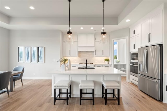 kitchen with white cabinetry, tasteful backsplash, a raised ceiling, pendant lighting, and stainless steel appliances