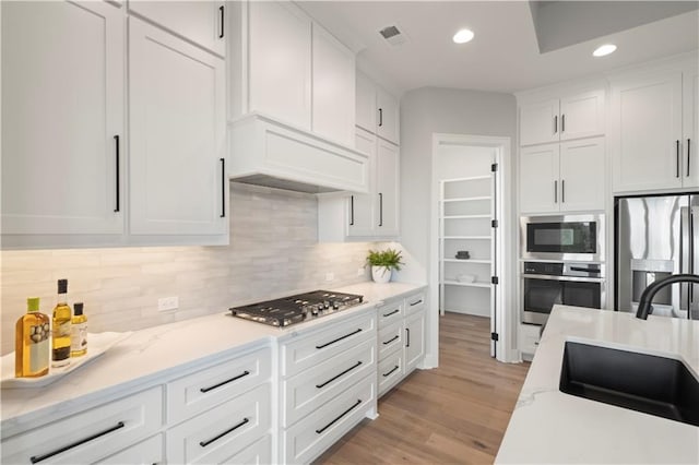 kitchen featuring stainless steel appliances, sink, white cabinets, and decorative backsplash