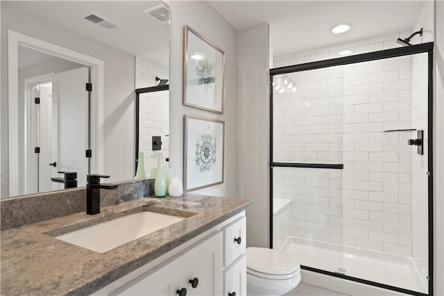 bathroom featuring vanity, a shower with shower door, and toilet