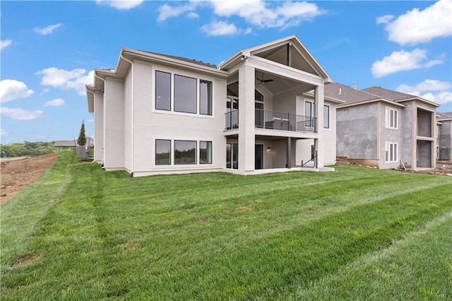 back of house featuring ceiling fan, a lawn, and a balcony