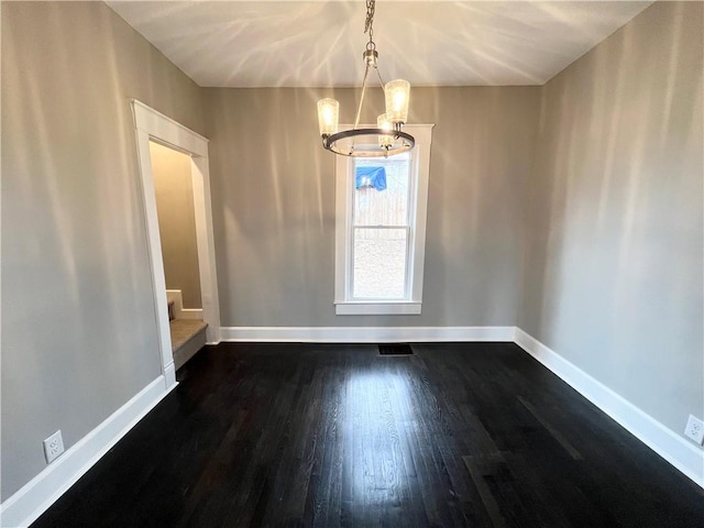 unfurnished dining area featuring an inviting chandelier and dark hardwood / wood-style flooring