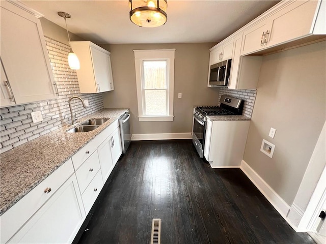 kitchen featuring white cabinetry, sink, decorative light fixtures, and appliances with stainless steel finishes