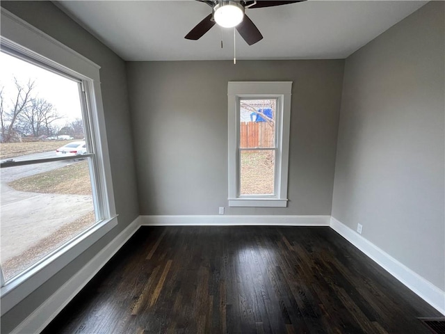 empty room featuring dark wood-type flooring, ceiling fan, and a wealth of natural light