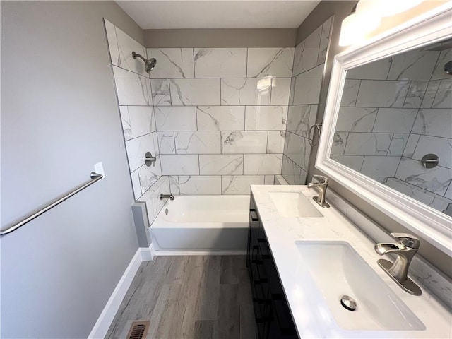 bathroom with vanity, tiled shower / bath combo, and wood-type flooring