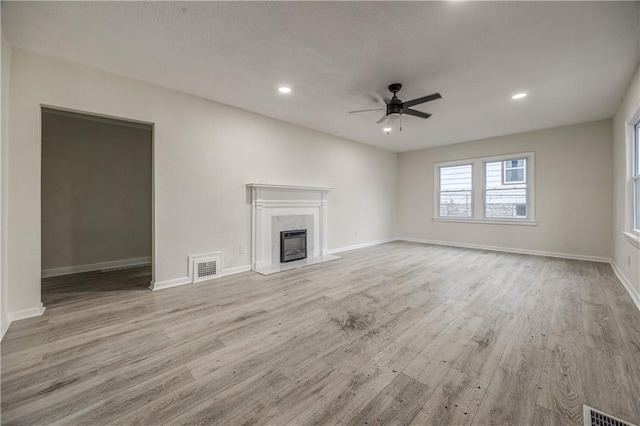 unfurnished living room featuring a fireplace, ceiling fan, and light hardwood / wood-style flooring