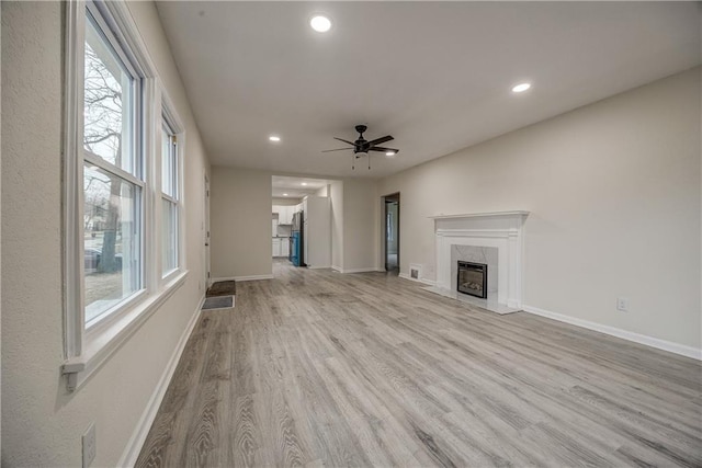 unfurnished living room featuring a fireplace, light hardwood / wood-style floors, and a wealth of natural light