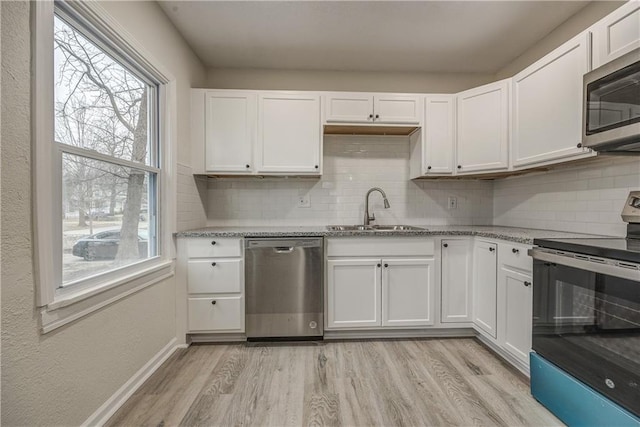 kitchen with white cabinetry, appliances with stainless steel finishes, sink, and light stone counters