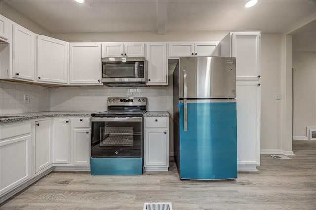 kitchen with appliances with stainless steel finishes, white cabinets, and light hardwood / wood-style flooring