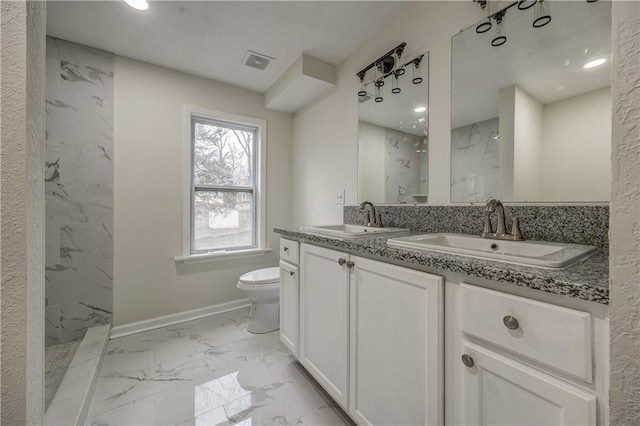 bathroom with tiled shower, vanity, and toilet