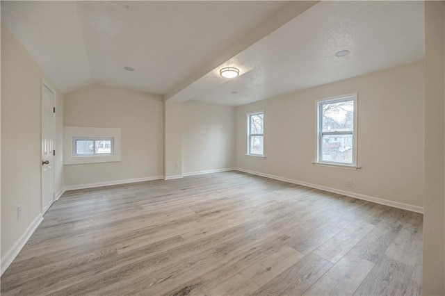 empty room featuring vaulted ceiling and light wood-type flooring