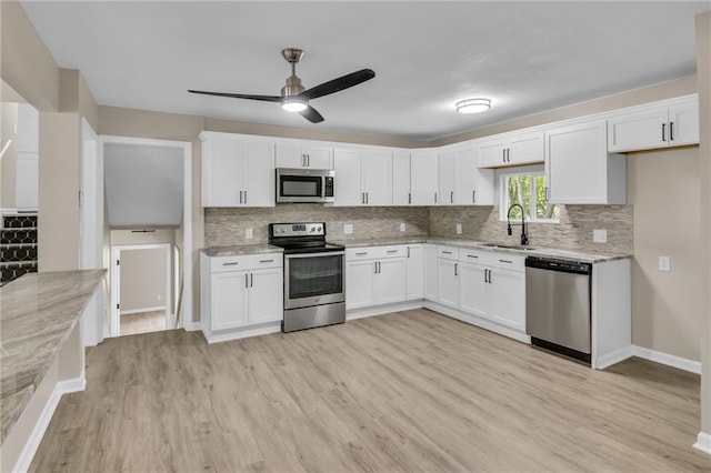 kitchen featuring appliances with stainless steel finishes, sink, white cabinets, and light stone counters