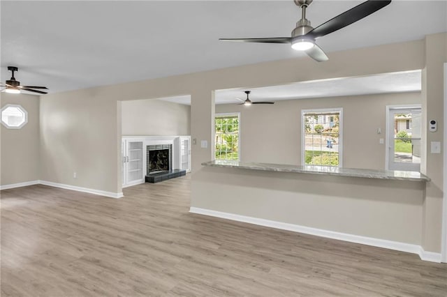 unfurnished living room featuring ceiling fan, a healthy amount of sunlight, and wood-type flooring