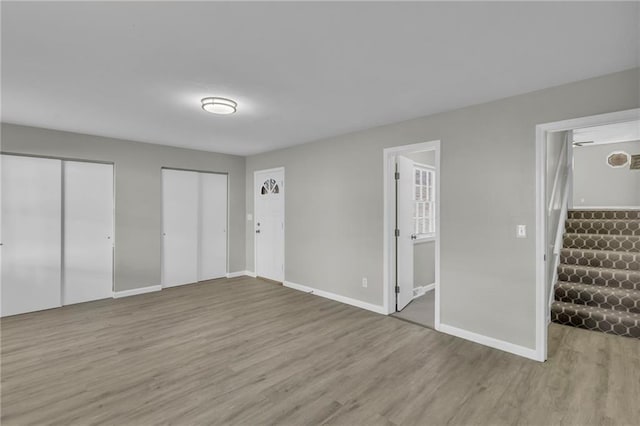 unfurnished bedroom featuring light hardwood / wood-style flooring and multiple closets