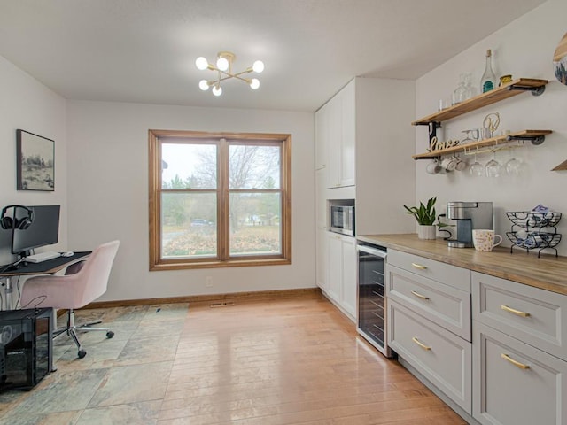 office area featuring an inviting chandelier, bar area, beverage cooler, and light wood-type flooring