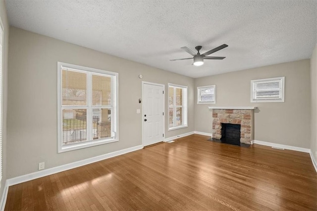 unfurnished living room featuring hardwood / wood-style flooring, a fireplace, a textured ceiling, and ceiling fan