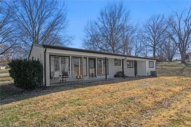 single story home with a front yard, central AC unit, brick siding, and a sunroom