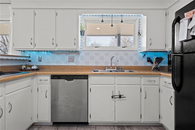 kitchen with backsplash, stainless steel dishwasher, freestanding refrigerator, white cabinets, and a sink