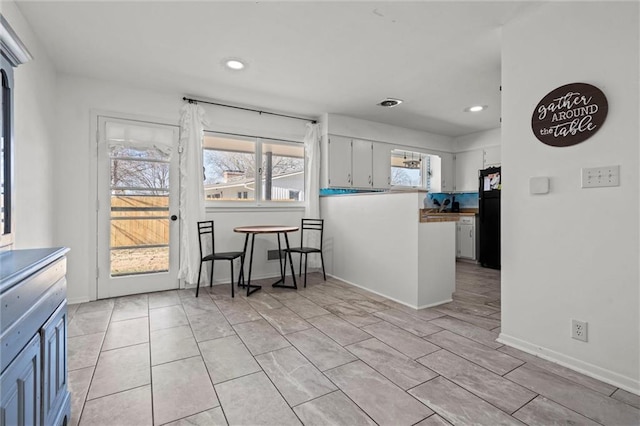 kitchen with baseboards, light tile patterned floors, recessed lighting, a peninsula, and freestanding refrigerator