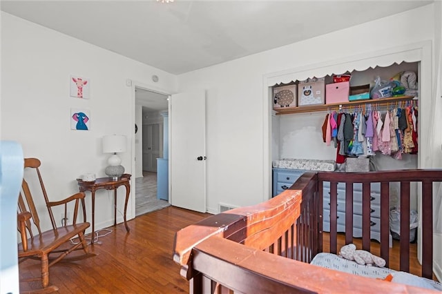 bedroom featuring a closet, baseboards, visible vents, and wood finished floors