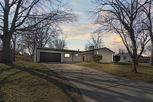 mid-century home with a garage, a lawn, and driveway