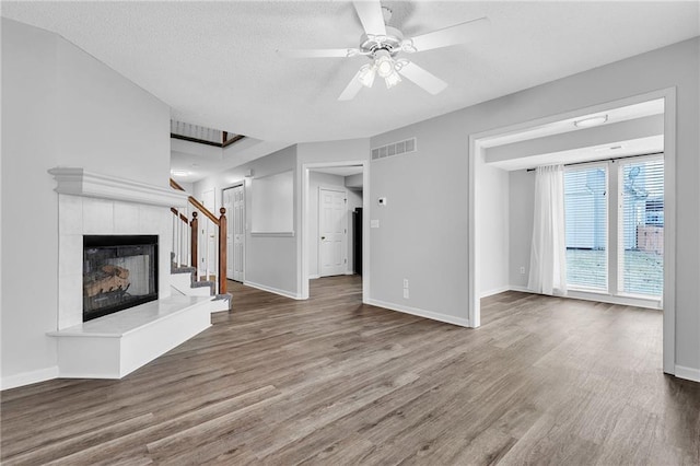 unfurnished living room with hardwood / wood-style flooring, a tile fireplace, and ceiling fan