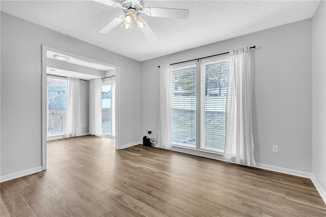 unfurnished room featuring hardwood / wood-style floors, plenty of natural light, and a textured ceiling