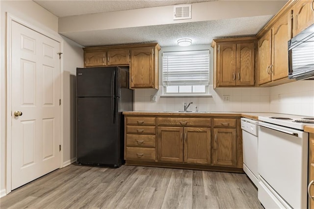 kitchen with sink, backsplash, light hardwood / wood-style flooring, and black appliances