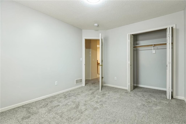 unfurnished bedroom featuring light colored carpet, a closet, and a textured ceiling