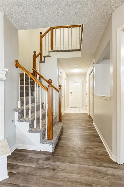 staircase with wood-type flooring and a textured ceiling