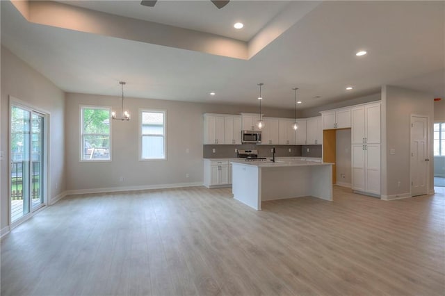 kitchen featuring open floor plan, stainless steel appliances, light wood-style flooring, and baseboards