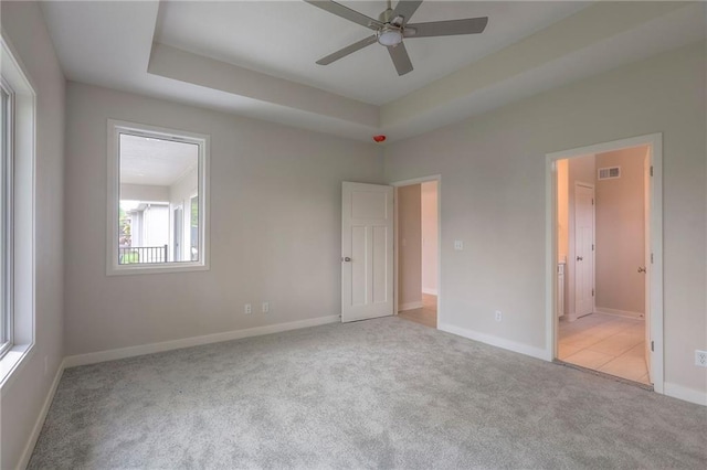 unfurnished bedroom featuring a raised ceiling, visible vents, carpet floors, and baseboards